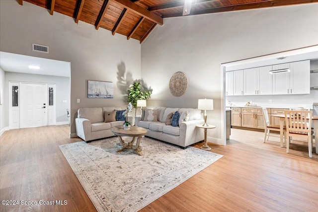 living room featuring light hardwood / wood-style floors, beam ceiling, and high vaulted ceiling