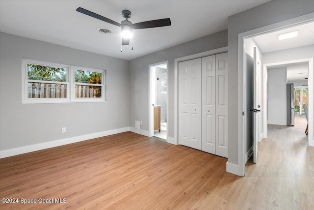 unfurnished bedroom with a closet, light hardwood / wood-style floors, multiple windows, and ceiling fan