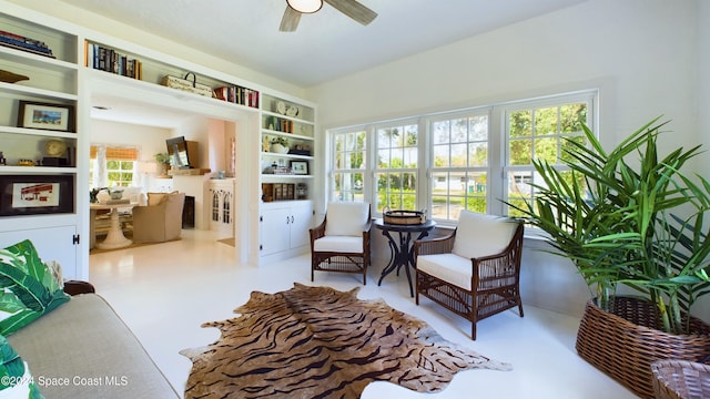 living area with built in features, ceiling fan, and a healthy amount of sunlight