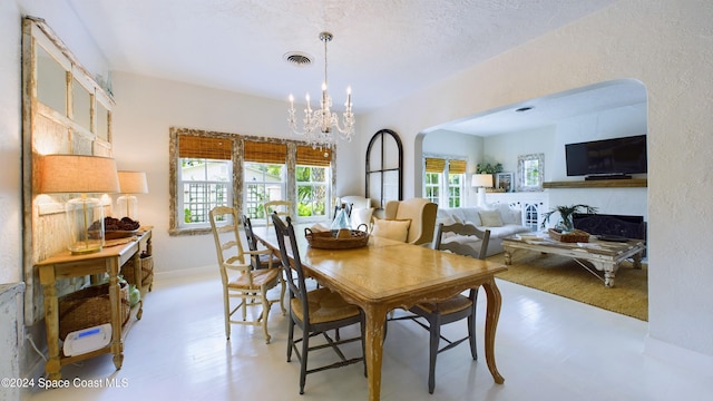 dining room featuring a textured ceiling, a notable chandelier, light hardwood / wood-style floors, and plenty of natural light