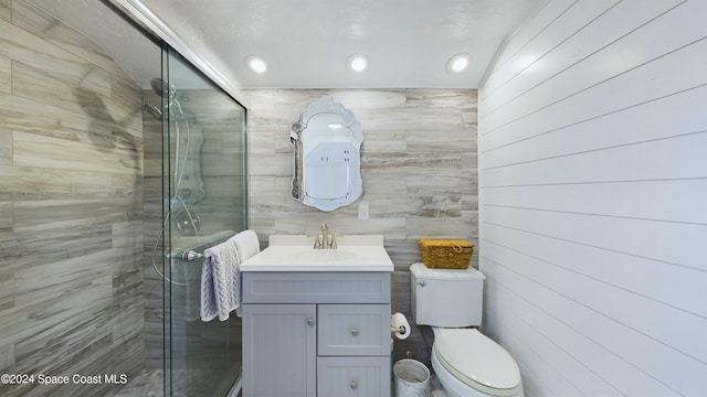 bathroom featuring a shower with door, vanity, and toilet