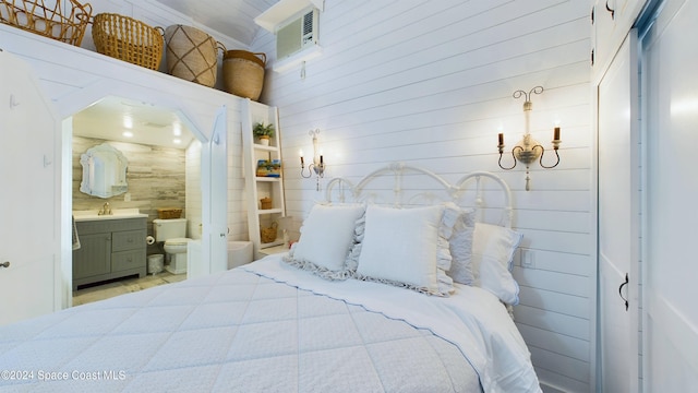 bedroom with connected bathroom, wood walls, and sink