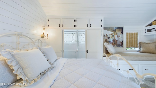 bedroom featuring wooden walls, vaulted ceiling, and a closet