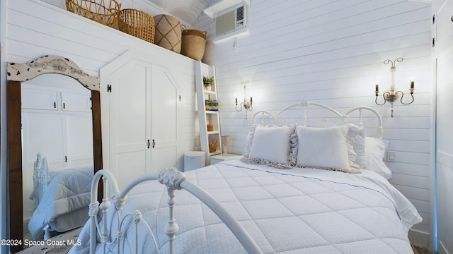 bedroom featuring a wall unit AC and wooden walls