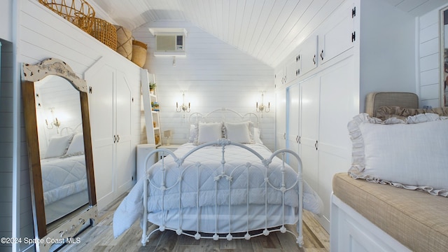 bedroom featuring wooden walls, lofted ceiling, and wood-type flooring