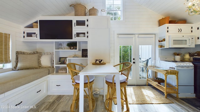 dining area featuring french doors, light hardwood / wood-style flooring, wooden walls, and vaulted ceiling