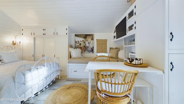 bedroom with wood walls, light wood-type flooring, lofted ceiling, and a closet