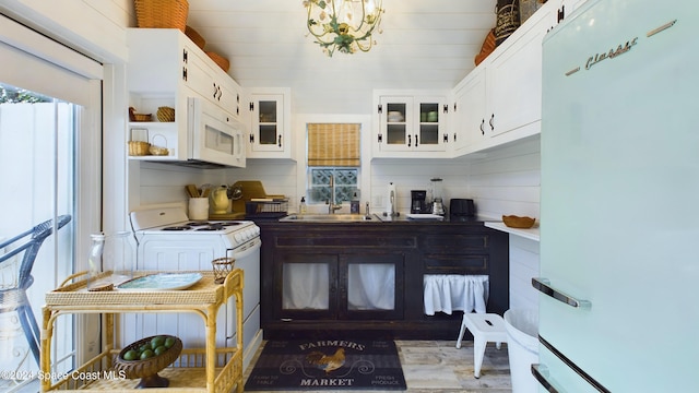 kitchen with white cabinetry, a notable chandelier, white appliances, and backsplash