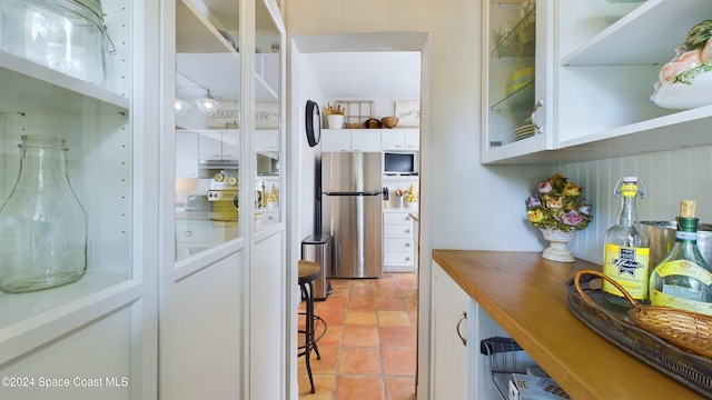 bar featuring white cabinets and stainless steel refrigerator