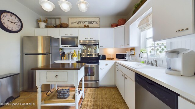 kitchen with white cabinetry, appliances with stainless steel finishes, sink, and pendant lighting