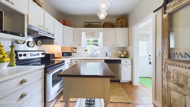 kitchen featuring stainless steel appliances, white cabinetry, sink, decorative light fixtures, and a center island