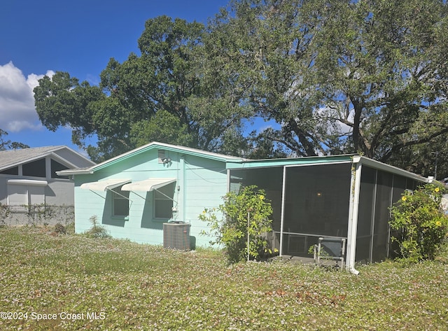 view of side of home with central air condition unit, a lawn, and a sunroom