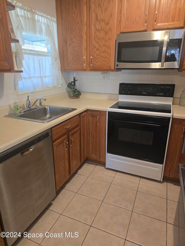 kitchen with sink, stainless steel appliances, backsplash, and light tile patterned floors