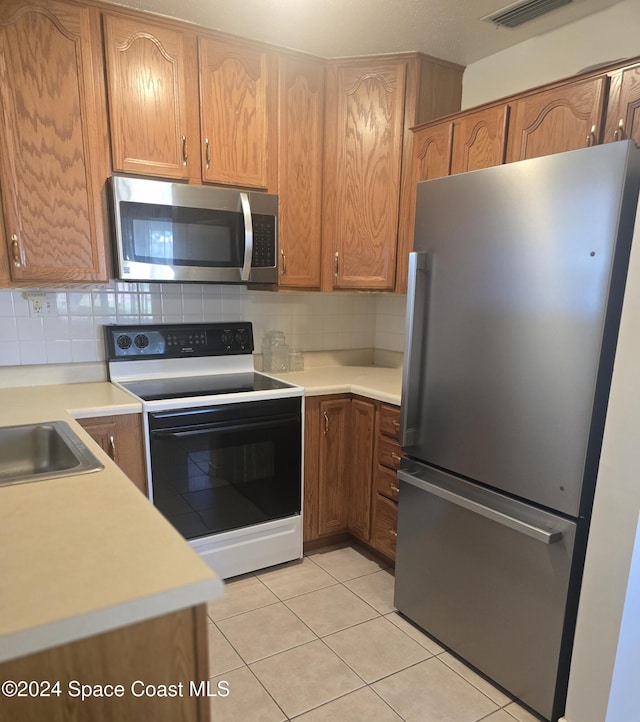 kitchen with sink, stainless steel appliances, decorative backsplash, and light tile patterned flooring