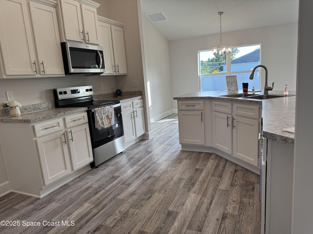 930 San Filippo Dr SE, Palm Bay, FL 32909 - kitchen with stainless steel appliances, a chandelier, wood finished floors, pendant lighting, and white cabinets