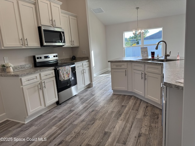 930 San Filippo Dr SE, Palm Bay, FL 32909 - kitchen with stainless steel appliances, a chandelier, wood finished floors, pendant lighting, and white cabinets