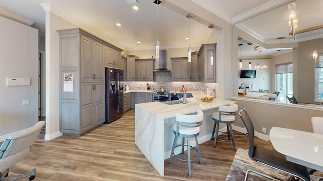 kitchen featuring a kitchen breakfast bar, black refrigerator with ice dispenser, kitchen peninsula, decorative light fixtures, and gray cabinets