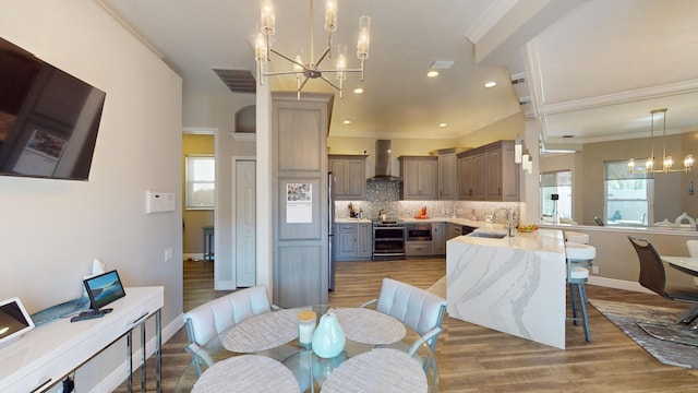 dining area featuring a healthy amount of sunlight, wood-type flooring, sink, and a chandelier