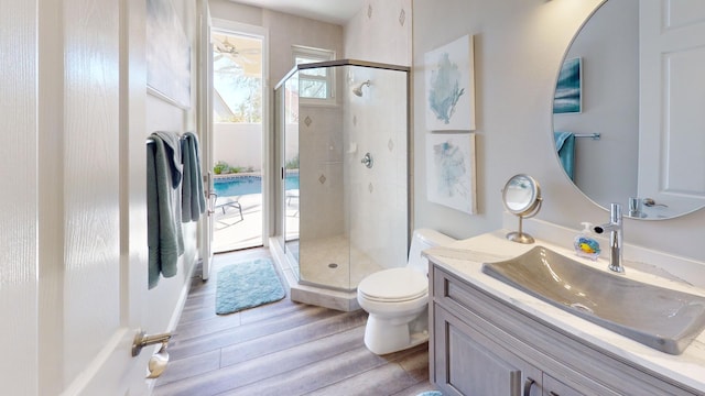 bathroom featuring vanity, wood-type flooring, a shower with shower door, and toilet