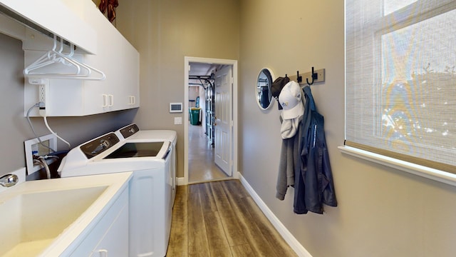 washroom featuring washing machine and clothes dryer, dark hardwood / wood-style flooring, cabinets, and sink