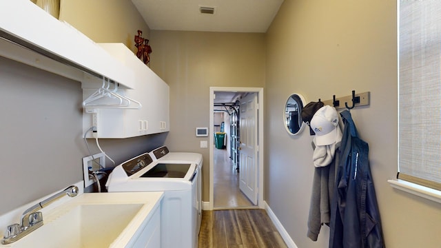 laundry area featuring cabinets, washing machine and dryer, sink, and dark wood-type flooring