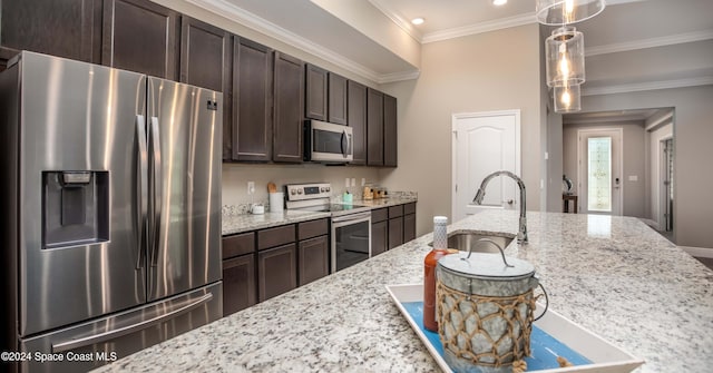 kitchen with dark brown cabinets, ornamental molding, pendant lighting, appliances with stainless steel finishes, and light stone counters