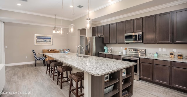 kitchen with a kitchen breakfast bar, a kitchen island with sink, sink, light hardwood / wood-style floors, and stainless steel appliances