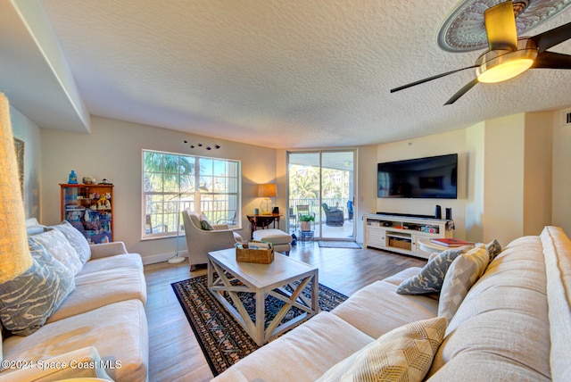 living room with a textured ceiling, wood-type flooring, and ceiling fan