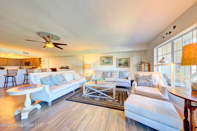 living room with a textured ceiling, hardwood / wood-style flooring, and ceiling fan