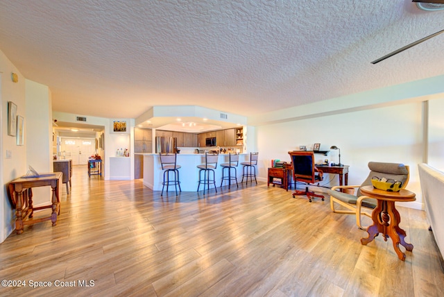 living area featuring a textured ceiling and light hardwood / wood-style floors