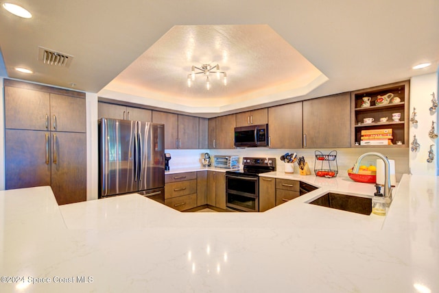 kitchen featuring appliances with stainless steel finishes, kitchen peninsula, sink, and a tray ceiling