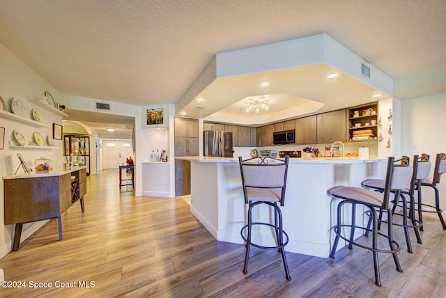 3360 S Atlantic Ave Unit 212, Cocoa Beach, FL 32931 - kitchen featuring open shelves, appliances with stainless steel finishes, light wood-style flooring, a peninsula, and a textured ceiling