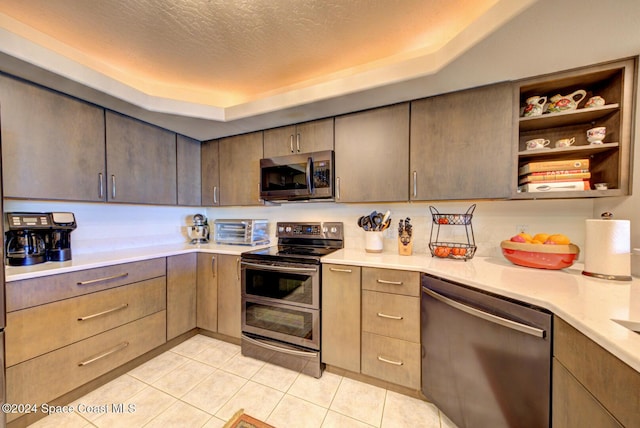 3360 S Atlantic Ave Unit 212, Cocoa Beach, FL 32931 - kitchen with appliances with stainless steel finishes, a tray ceiling, light tile patterned flooring, light countertops, and a textured ceiling