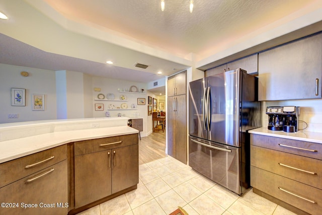 3360 S Atlantic Ave Unit 212, Cocoa Beach, FL 32931 - kitchen with freestanding refrigerator, light countertops, light tile patterned flooring, a textured ceiling, and brown cabinets