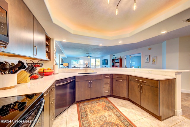 kitchen featuring sink, a textured ceiling, kitchen peninsula, stainless steel appliances, and light tile patterned floors