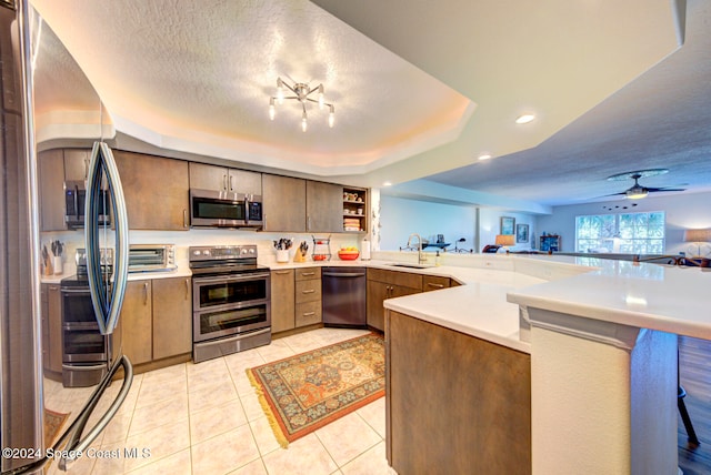 kitchen with a breakfast bar area, kitchen peninsula, stainless steel appliances, a textured ceiling, and ceiling fan