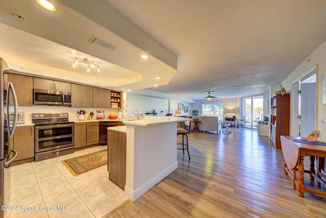 3360 S Atlantic Ave Unit 212, Cocoa Beach, FL 32931 - kitchen featuring appliances with stainless steel finishes, open floor plan, light countertops, open shelves, and a textured ceiling