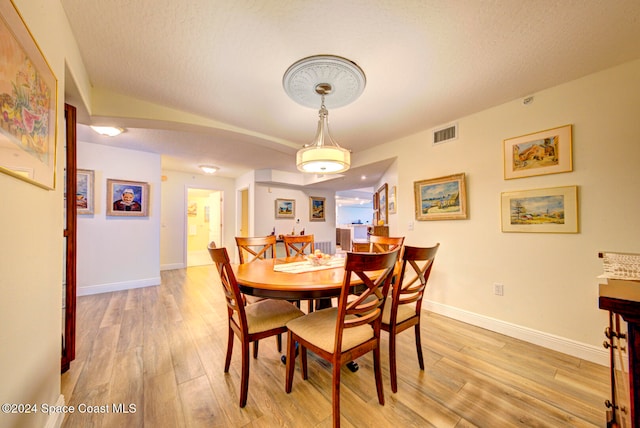 dining room featuring a textured ceiling and light wood-type flooring