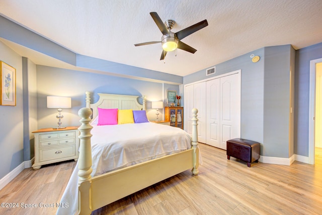 bedroom with light hardwood / wood-style flooring, a closet, a textured ceiling, and ceiling fan