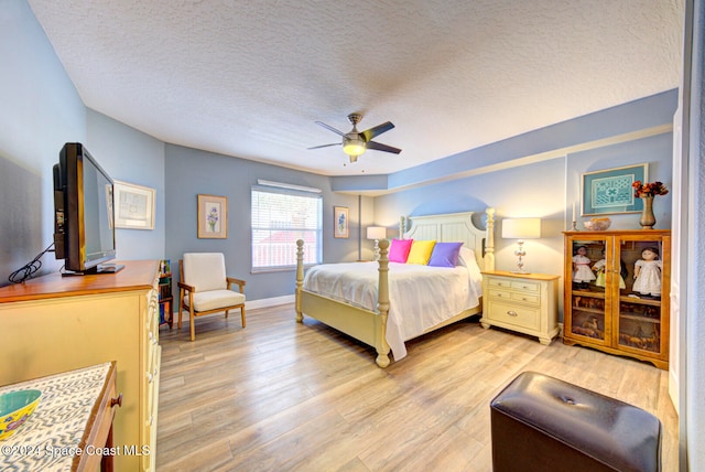 bedroom featuring light hardwood / wood-style flooring, a textured ceiling, and ceiling fan