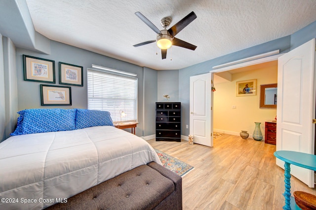 bedroom featuring light hardwood / wood-style floors, a textured ceiling, and ceiling fan