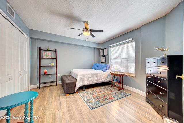 bedroom with light hardwood / wood-style flooring, a closet, a textured ceiling, and ceiling fan