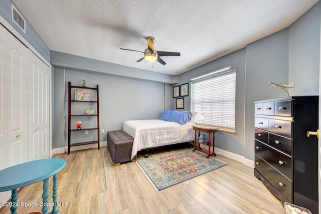 3360 S Atlantic Ave Unit 212, Cocoa Beach, FL 32931 - bedroom featuring a textured ceiling, light wood finished floors, baseboards, a closet, and ceiling fan