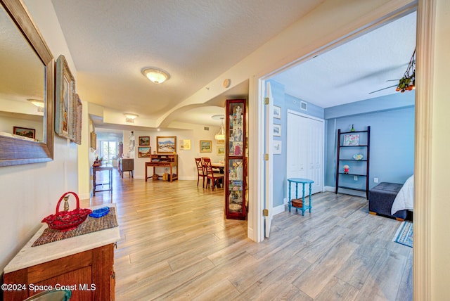 hall with light hardwood / wood-style flooring and a textured ceiling