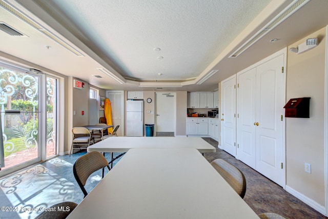 dining space with a raised ceiling and a textured ceiling