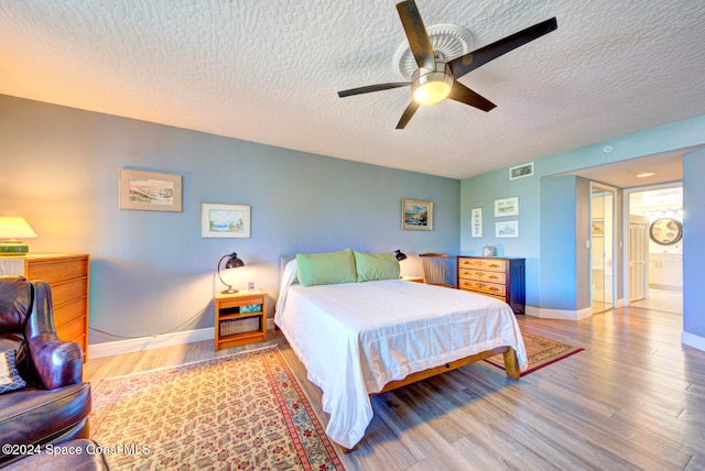 bedroom with hardwood / wood-style floors, ensuite bathroom, a textured ceiling, and ceiling fan