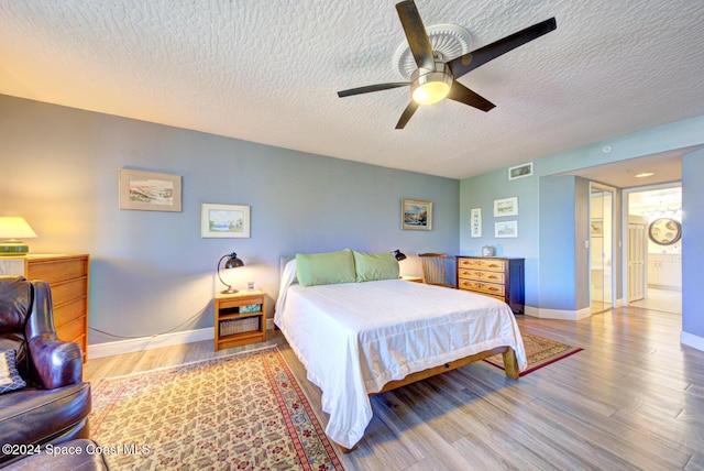 3360 S Atlantic Ave Unit 212, Cocoa Beach, FL 32931 - bedroom featuring a textured ceiling, wood finished floors, baseboards, ensuite bathroom, and ceiling fan