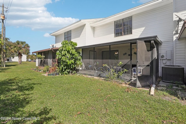 rear view of house with a yard, a sunroom, and central AC