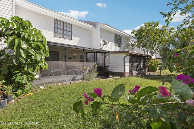 rear view of property with a yard, central air condition unit, and a sunroom