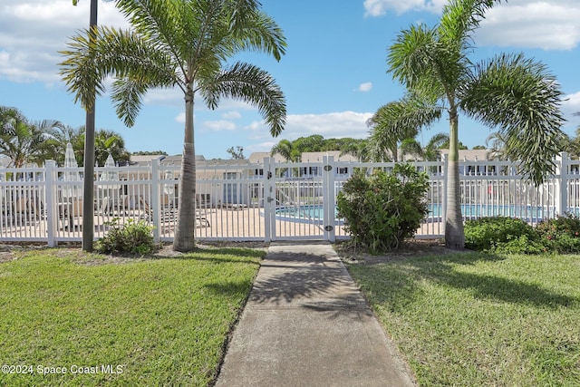 view of gate with a community pool and a lawn